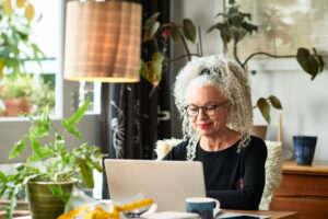 A business woman is looking something up in her company's intranet at a laptop in her home office.