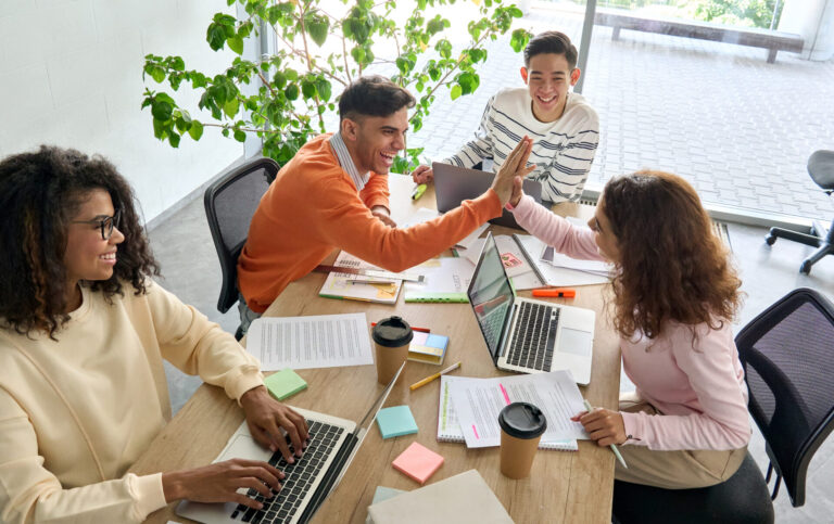 Happy team of office workers working together and giving each other a high five.