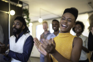 Smiling employees are clapping because they are having a great employee experience.