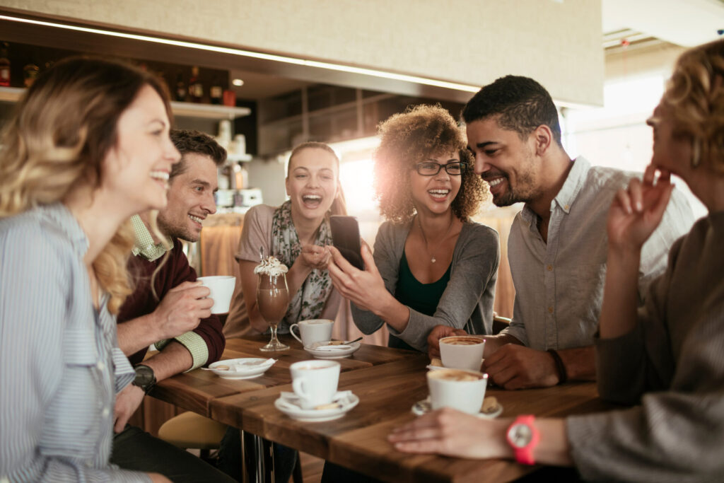 Eine Gruppe von Freund:innen sitzen im Café und unterhalten sich fließend in derselben Sprache.