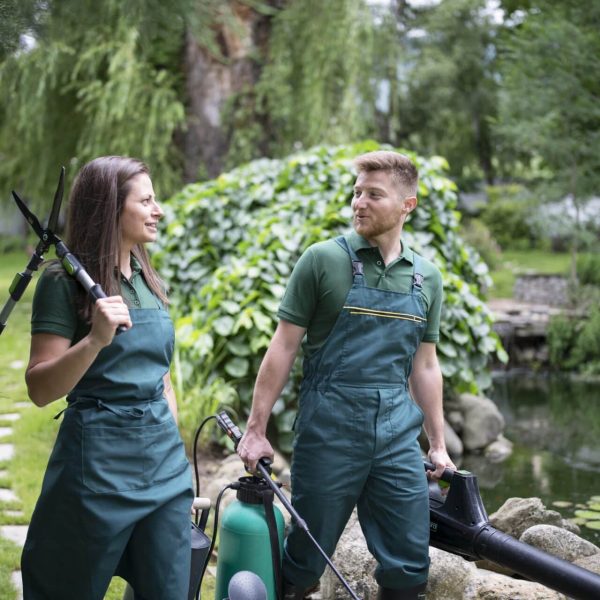 Man and woman are walking in garden and carrying gardening equipment.